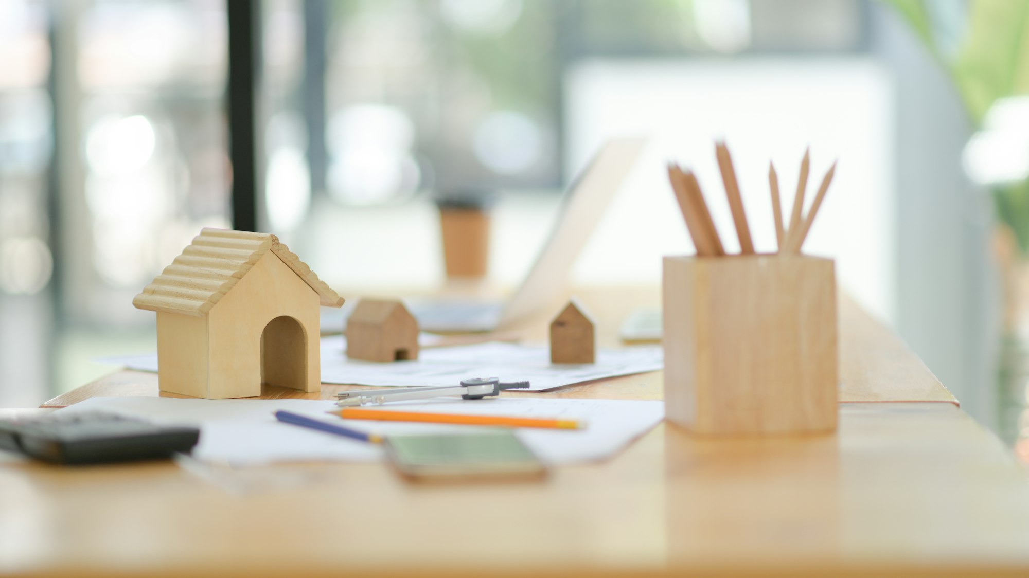 Mockup house drawing tools and wooden model house on desk in the office.